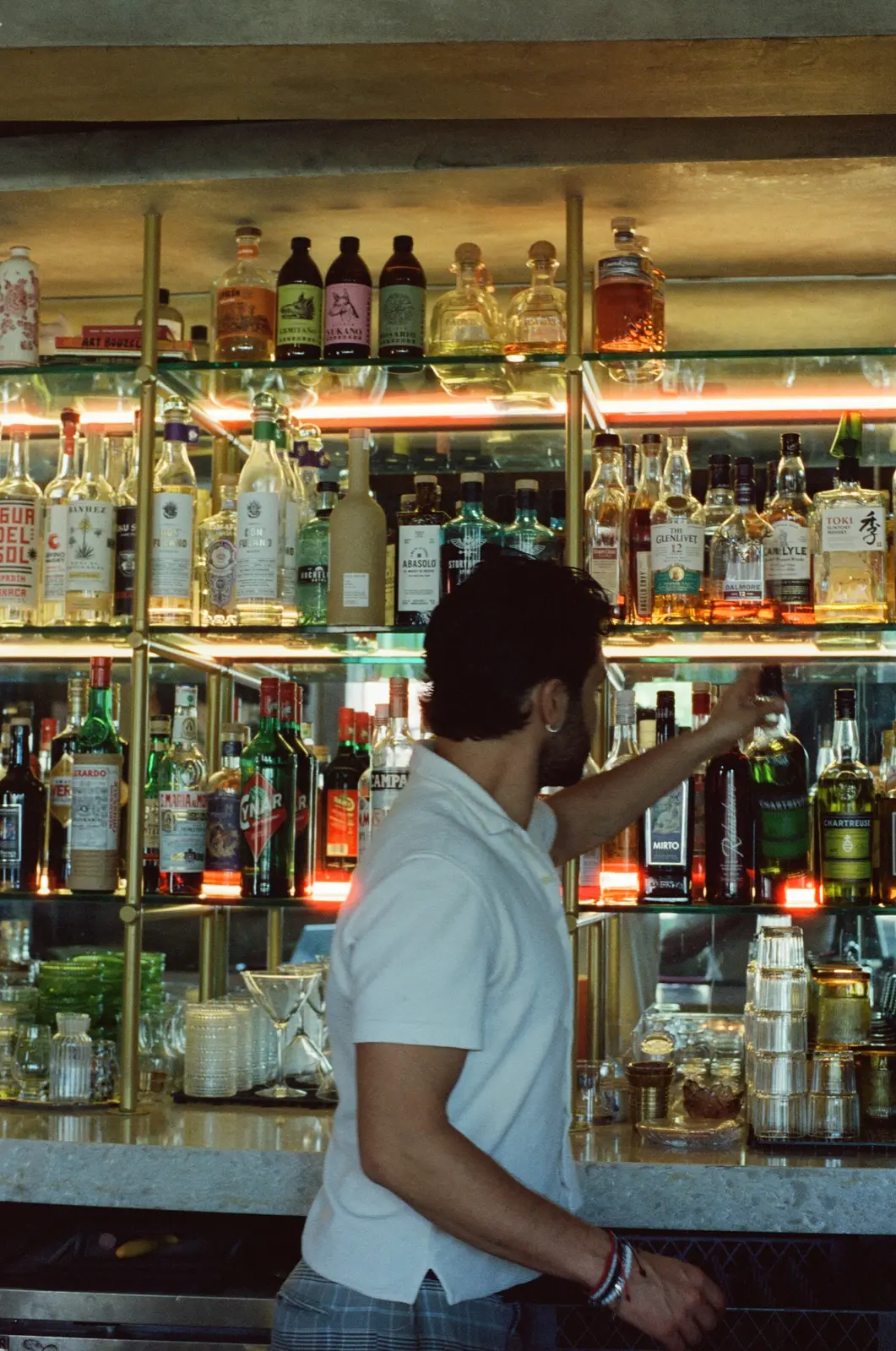 A hospitality professional selecting a bottle behind a restaurant bar