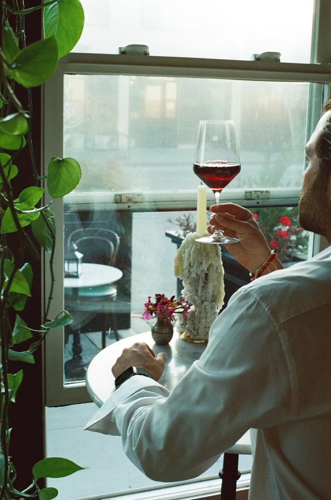 A restaurant guest holding a glass of wine by a window
